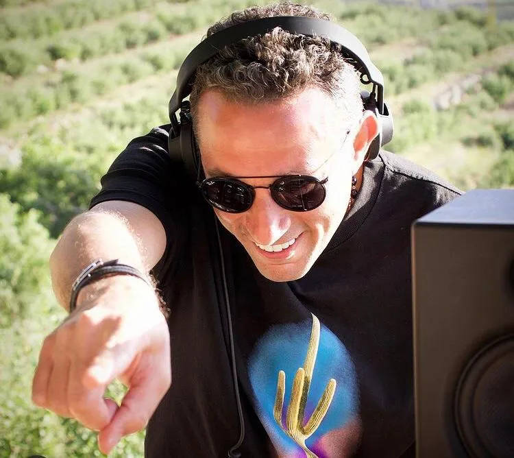 Waleed Nassif in headphones pointing toward the camera on an outdoor shoot