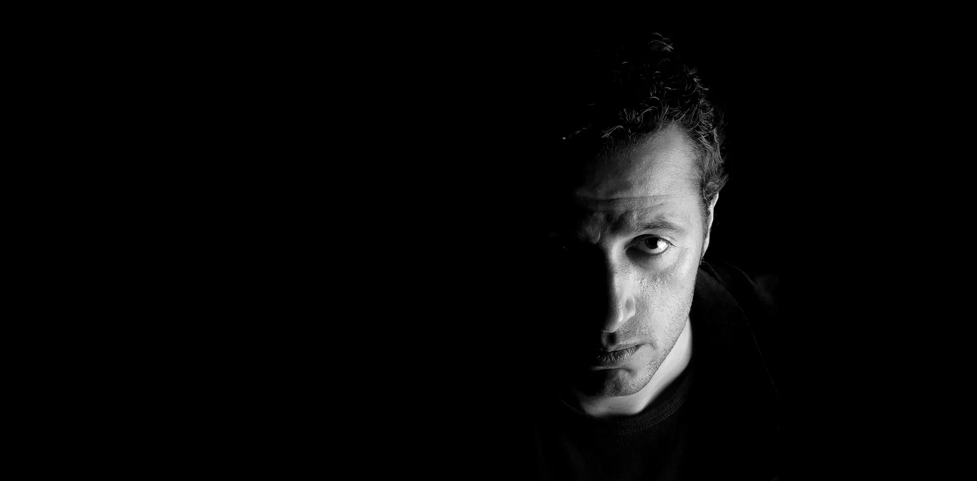 Black-and-white portrait of Waleed Nassif, half his face in light