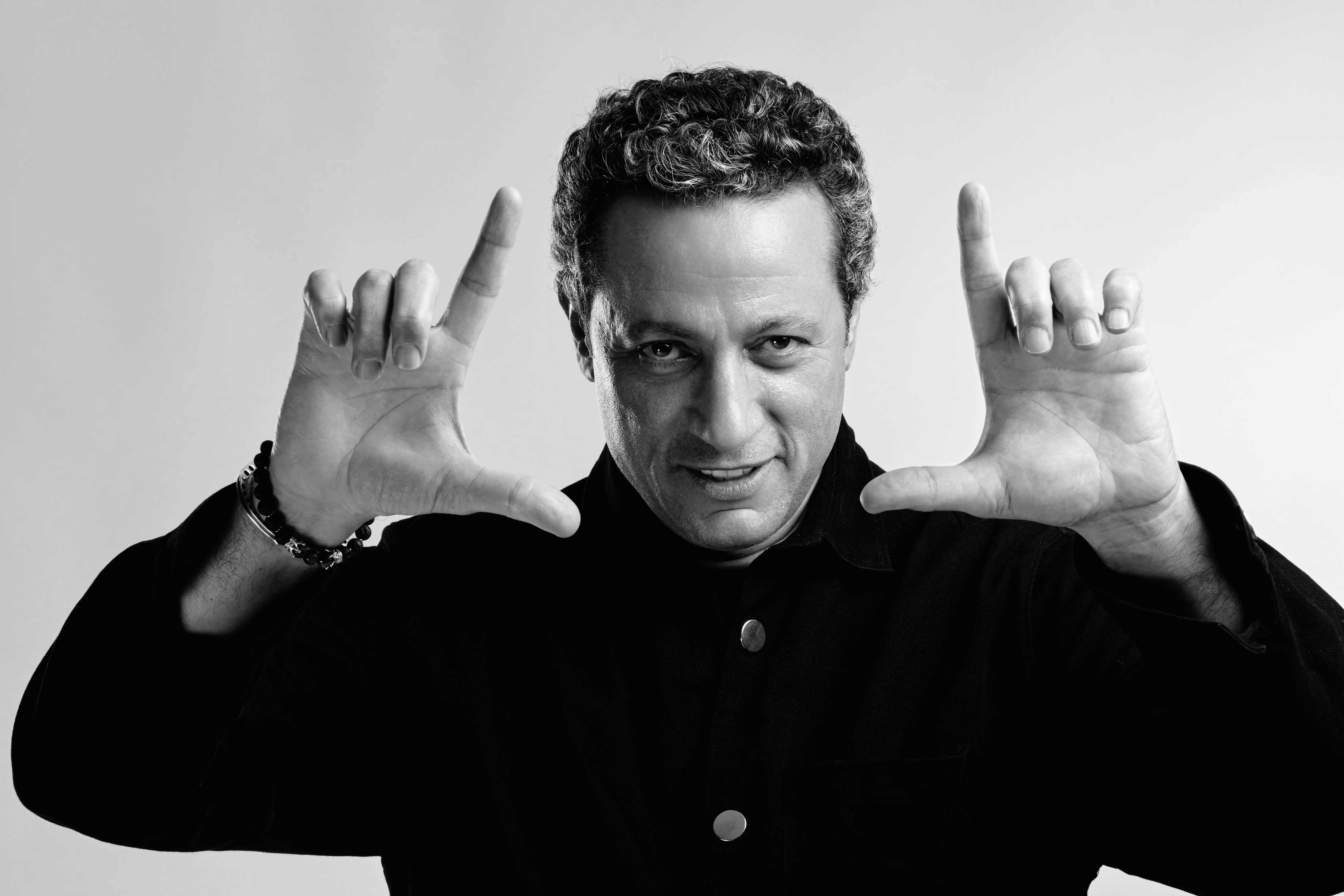 Black-and-white portrait of Waleed Nassif making a director's frame with his hands