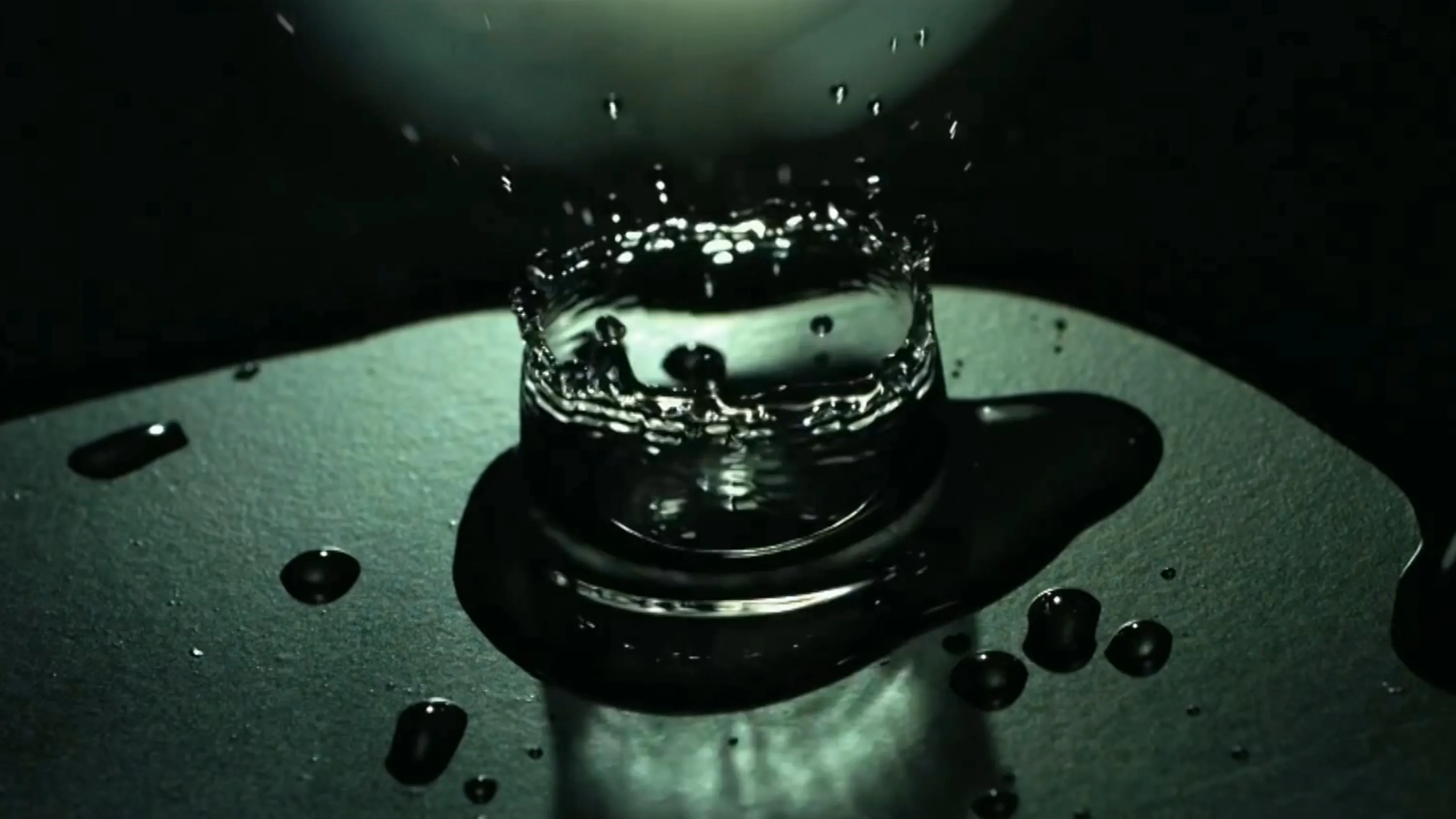 A water drop forming a crown splash on a dark surface, filmed at 2000 frames per second
