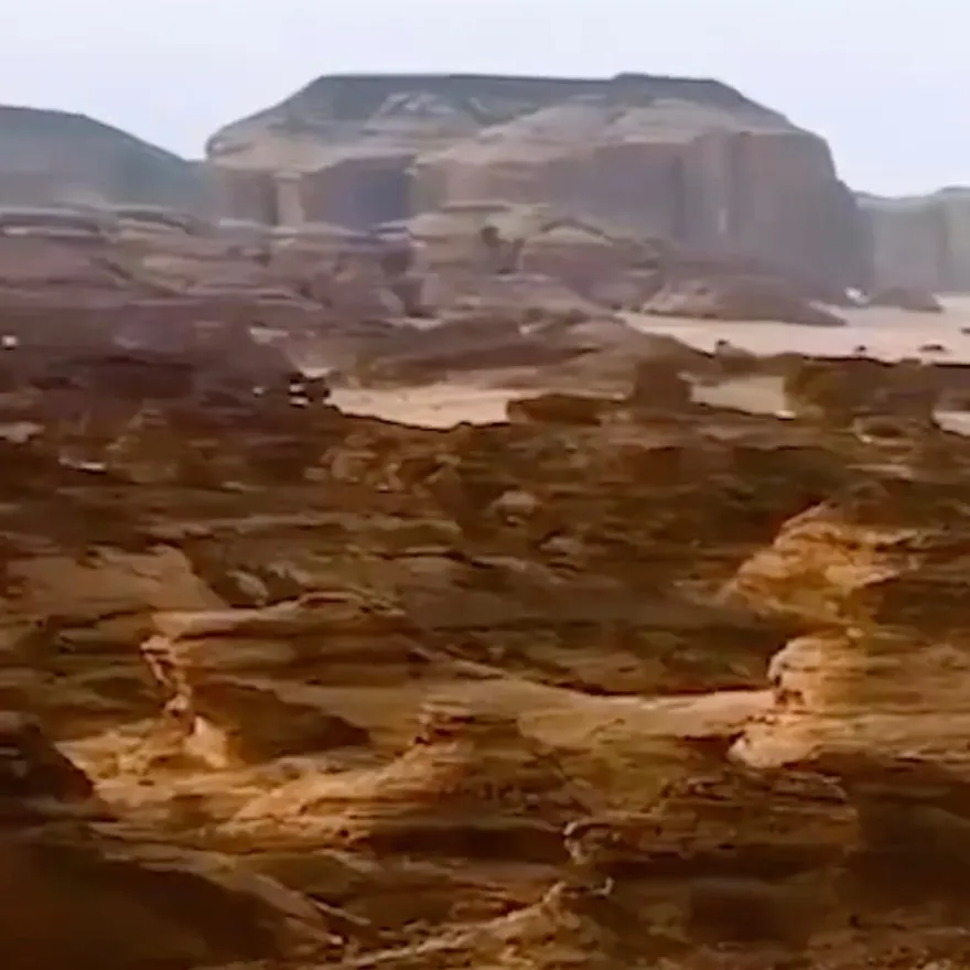 Sandstone outcrops below a flat-topped mesa in the desert, a frame from his live concerts showreel